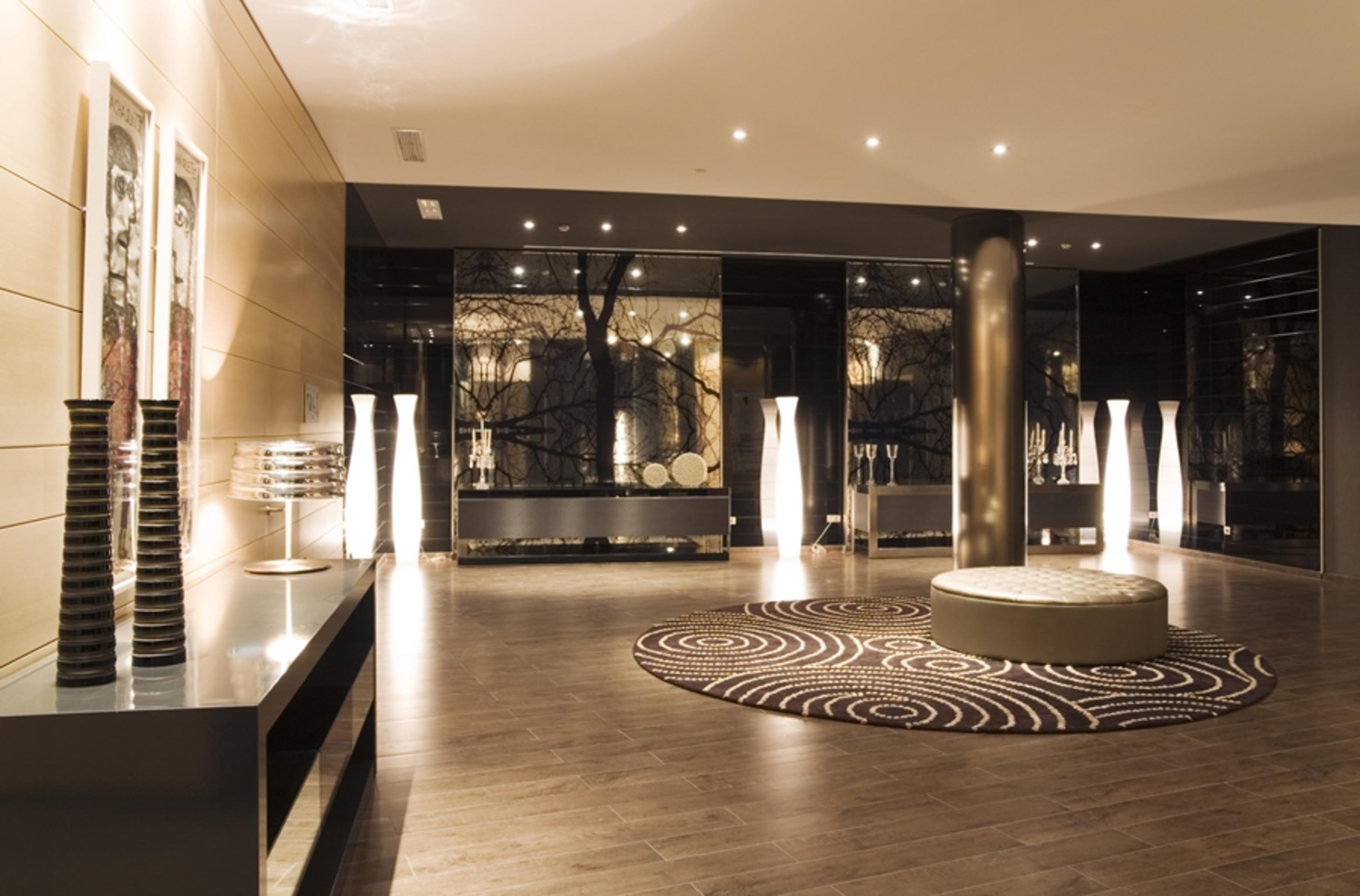 Eurostars Palace Córdoba Exterior foto The photo shows a modern interior space, likely a lobby or waiting area. The design features polished wooden flooring and sleek surfaces. There are tall, artistic light fixtures scattered throughout, contributing to a sophisticated ambiance. A round 