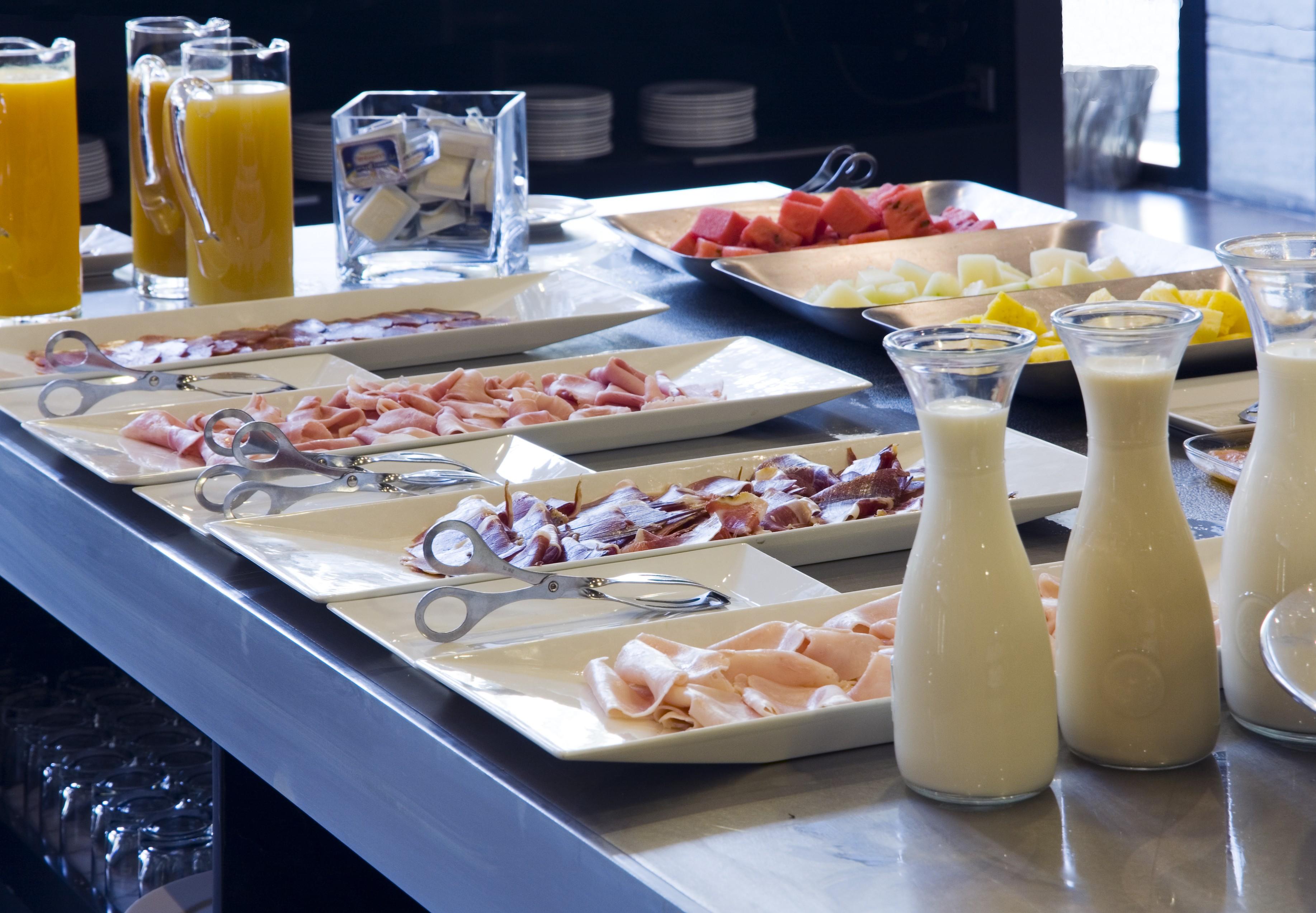 Eurostars Palace Córdoba Exterior foto The photo displays a buffet area with various food items arranged on a countertop. There are multiple plates featuring an assortment of sliced meats, likely including ham and possibly turkey or chicken. Additionally, two glass pitchers are filled wit