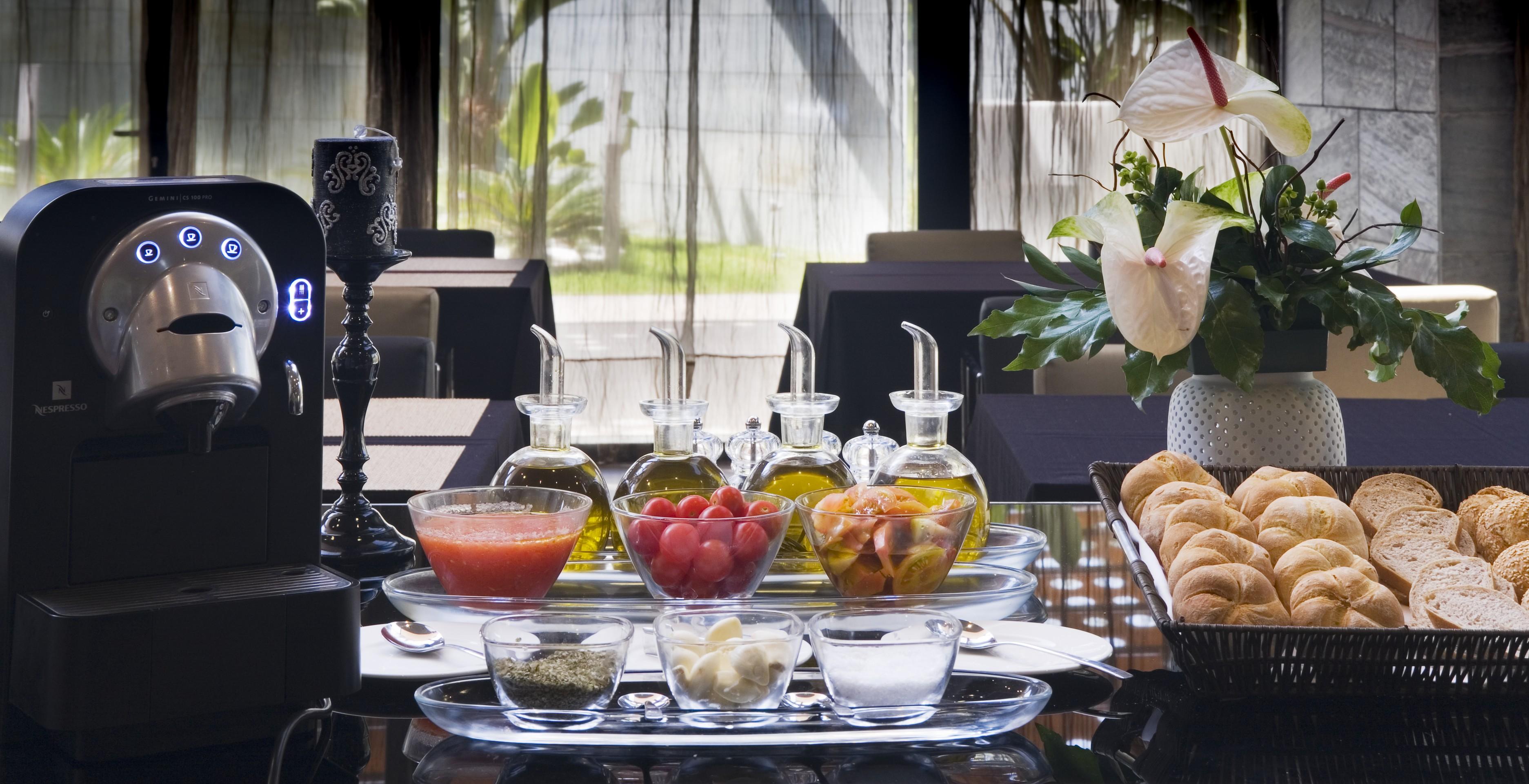 Eurostars Palace Córdoba Exterior foto The photo showcases a beautifully arranged dining setting. In the center, there are several glass containers filled with different types of oils, possibly olive oil. Accompanying them are small bowls containing various ingredients, including what app