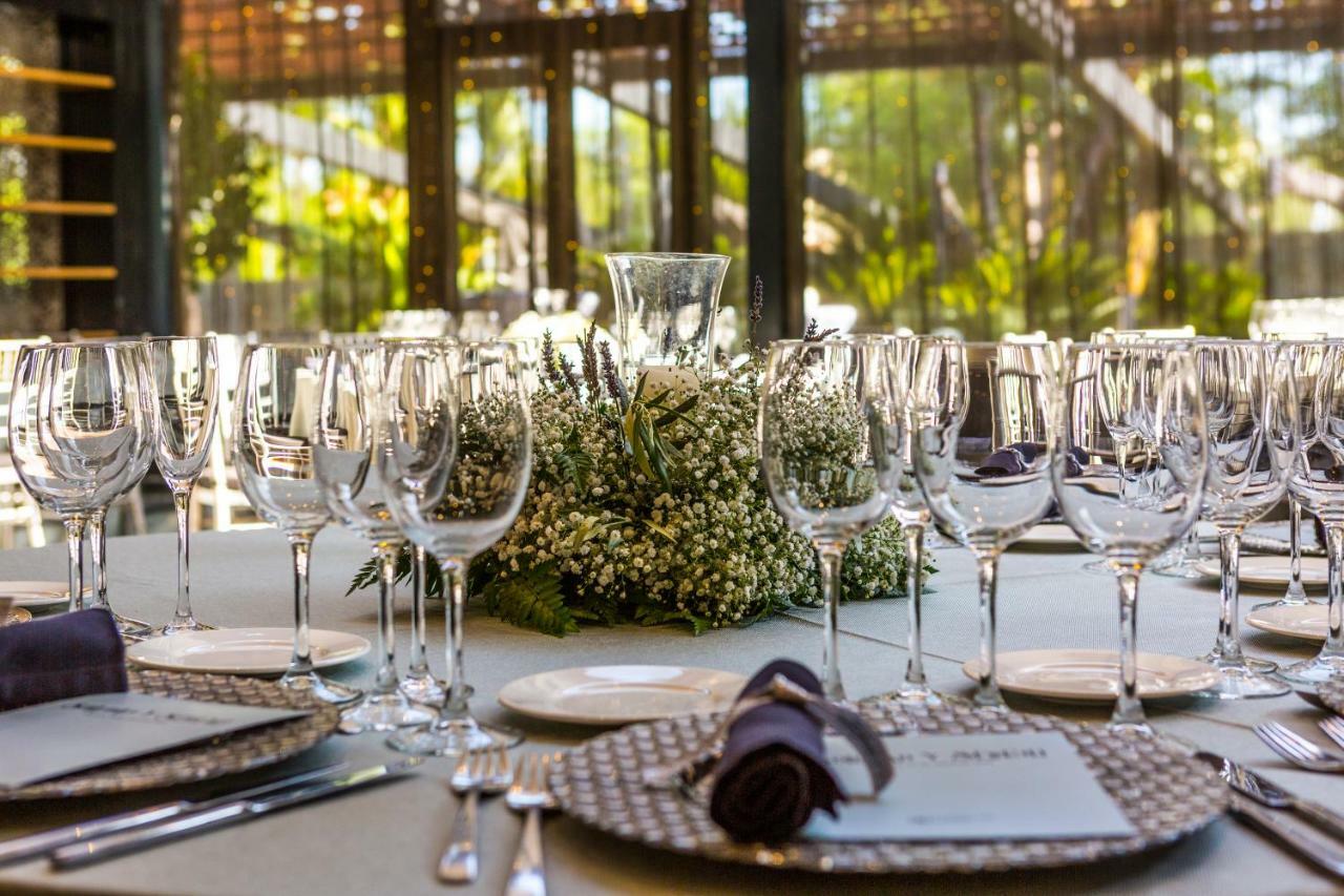 Eurostars Palace Córdoba Exterior foto The photo displays an elegantly set dining table arranged for a formal event. The table is adorned with a centerpiece made of white flowers and greenery, surrounded by numerous glassware, including wine glasses and water goblets. Each place setting i